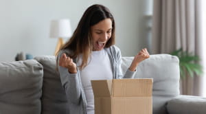Deals for key workers young woman excited opening parcel